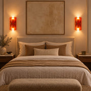 Pair of amber Auralis wall lamps beside a bed