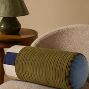 Sovana velvet neck-roll pillow in Olive Navy on an armchair